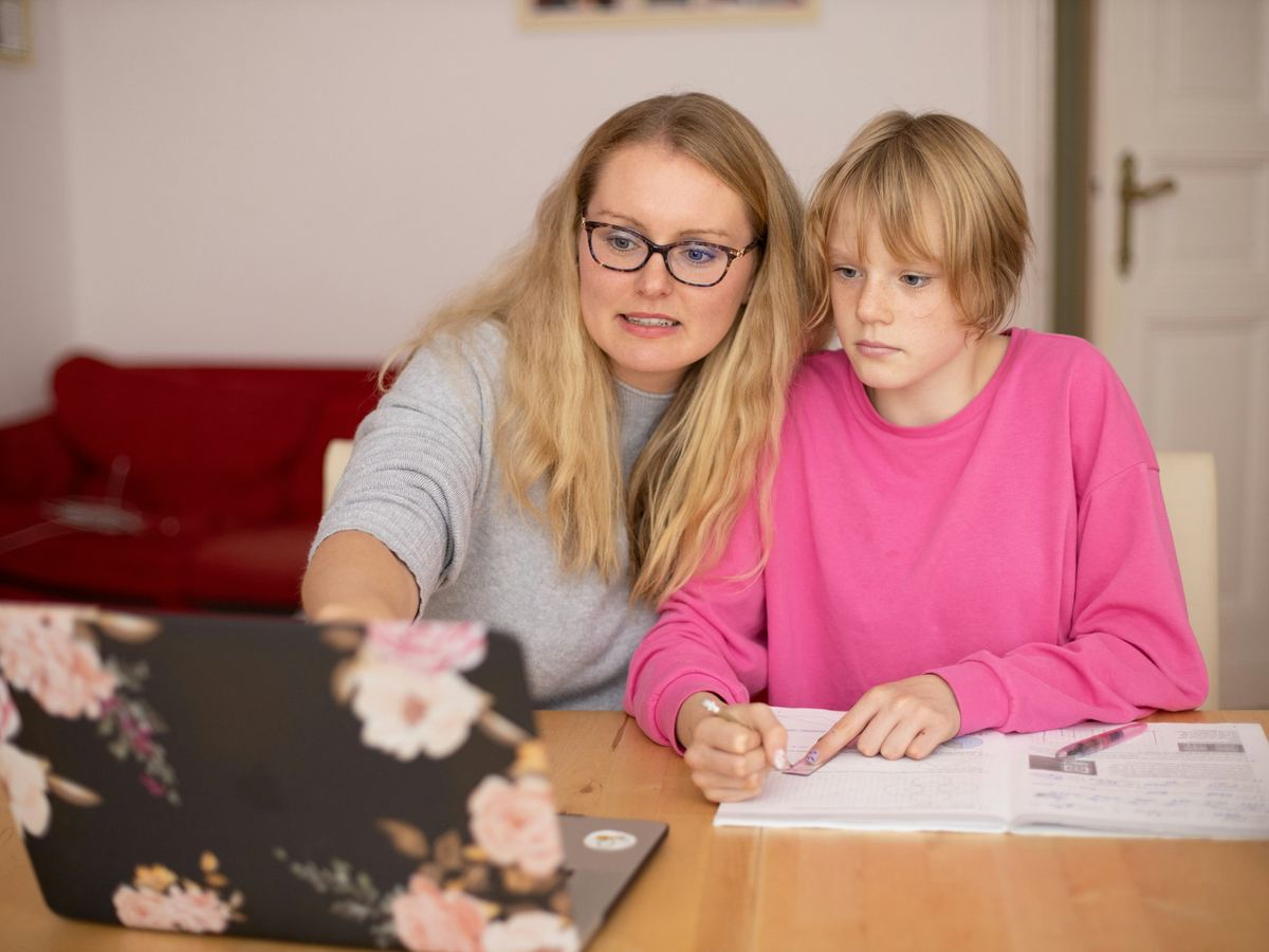 A woman and a girl work through a lesson together at a laptop