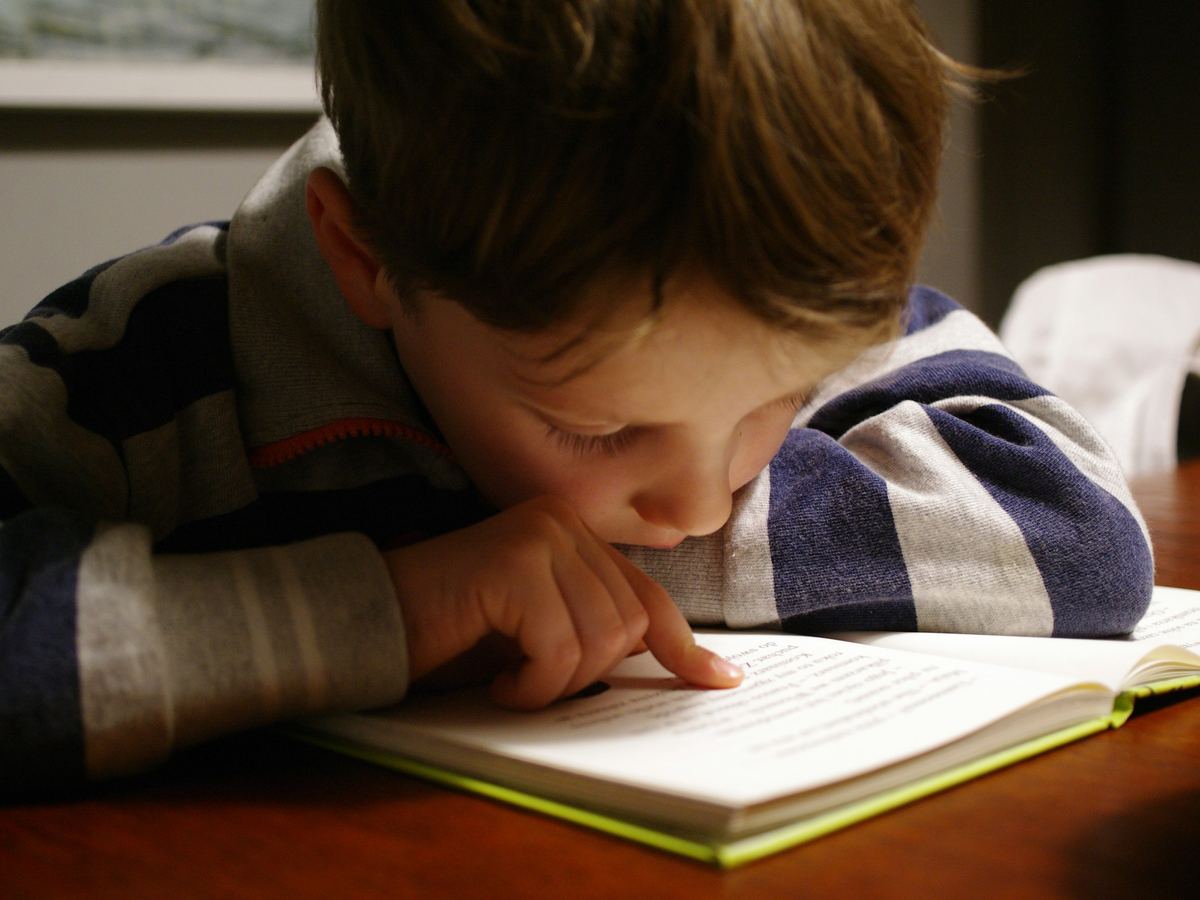 A boy follows the words in a book with his finger